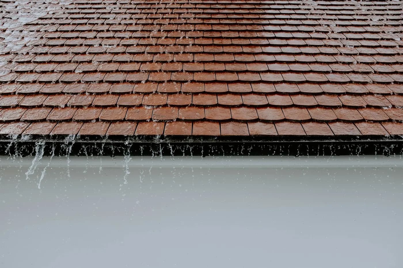 Rainwater running off the lower edge of a tiled roof