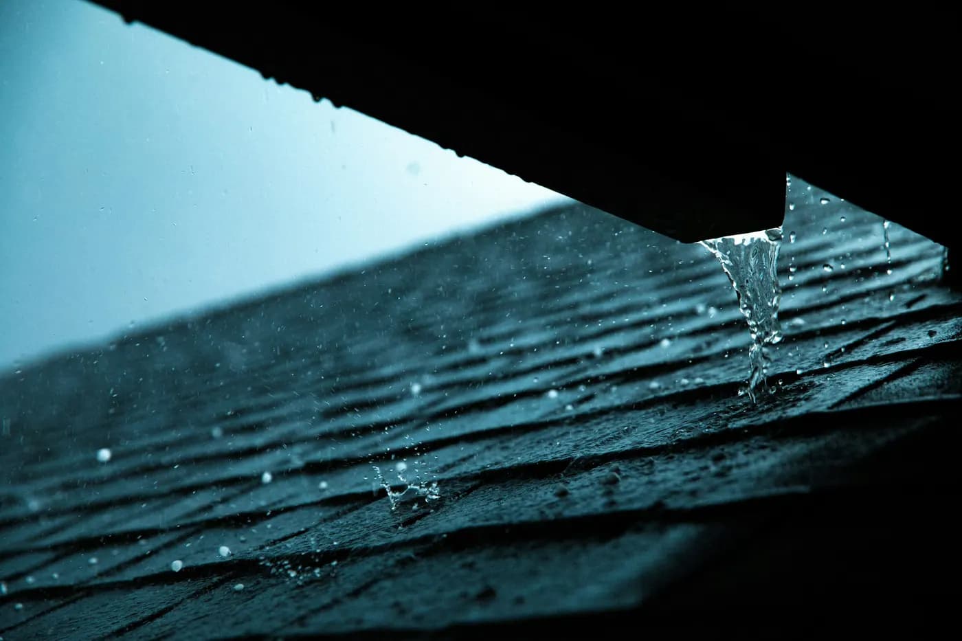 Rainwater running off the lower edge of an asphalt shingle roof
