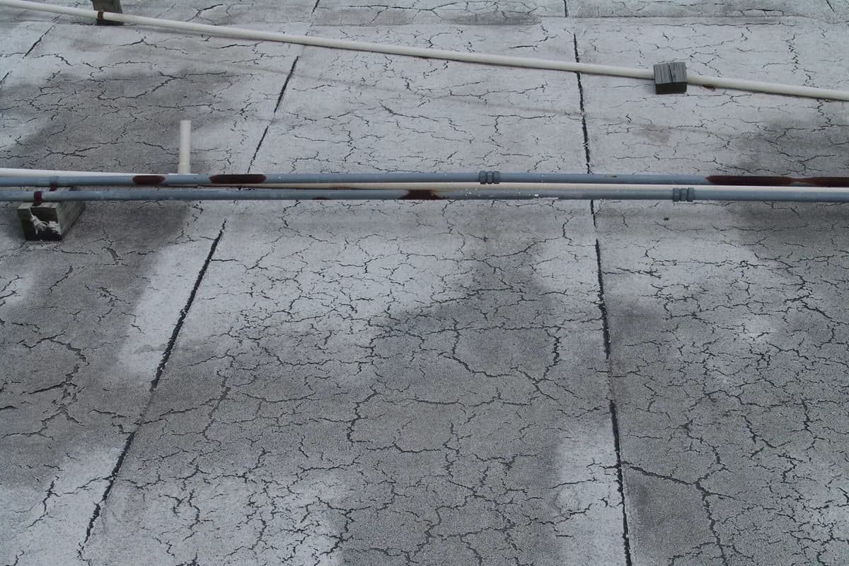 A weathered low-slope roof membrane with extensive surface cracking