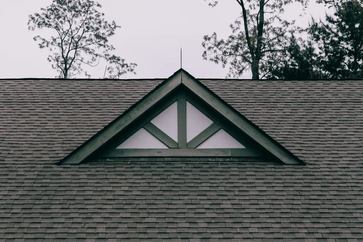 An asphalt shingle roof with a small decorative gable vent