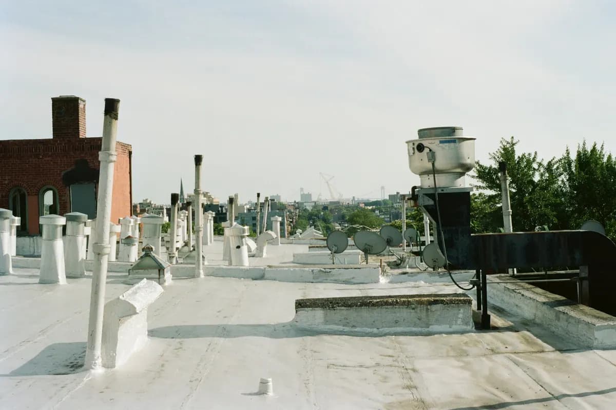 A flat commercial rooftop crowded with vent pipes and an exhaust fan
